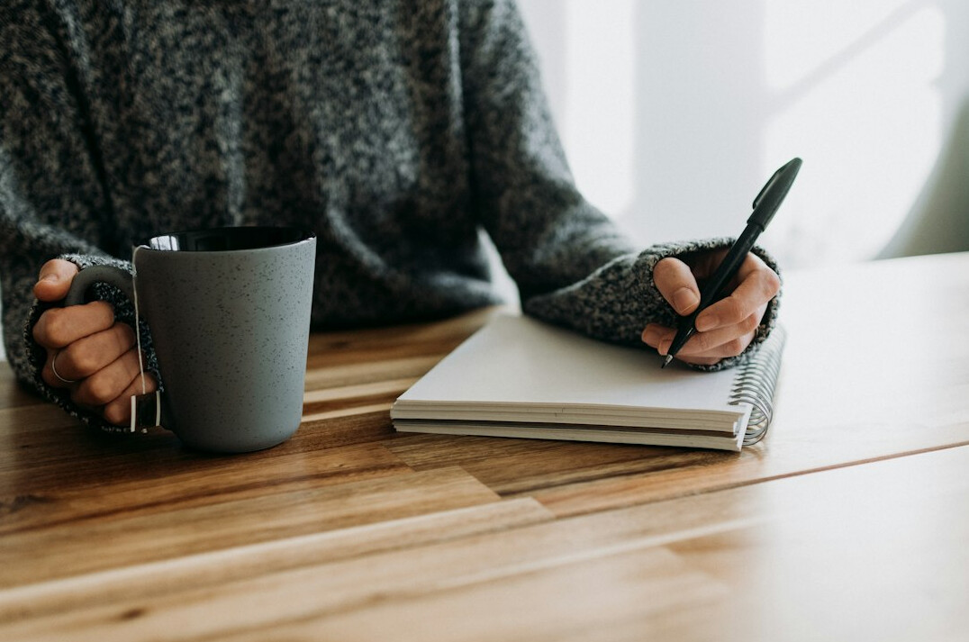 man writing notes in notebook